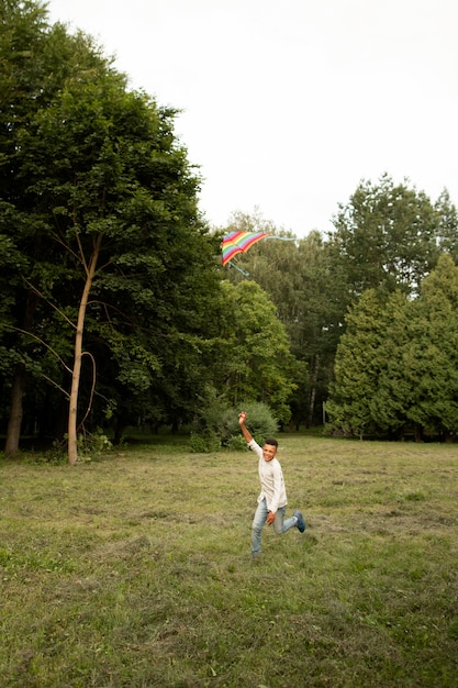 Long shot of happy boy having fun with a kite