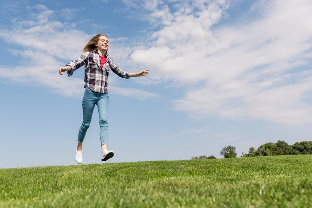 Long shot happy girl running on grass