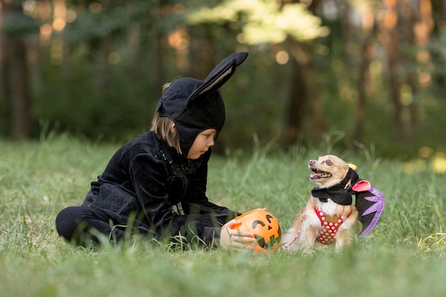 Long shot of little boy in bat costume and dog