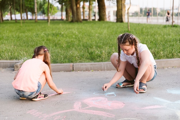 Long shot little girls drawing with chalk