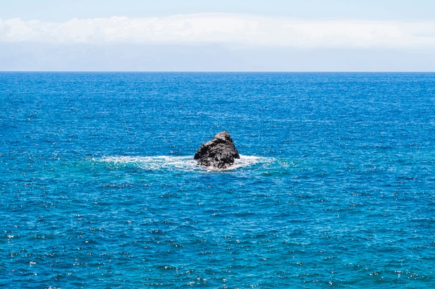 Free photo long shot lone rock in crystalline sea