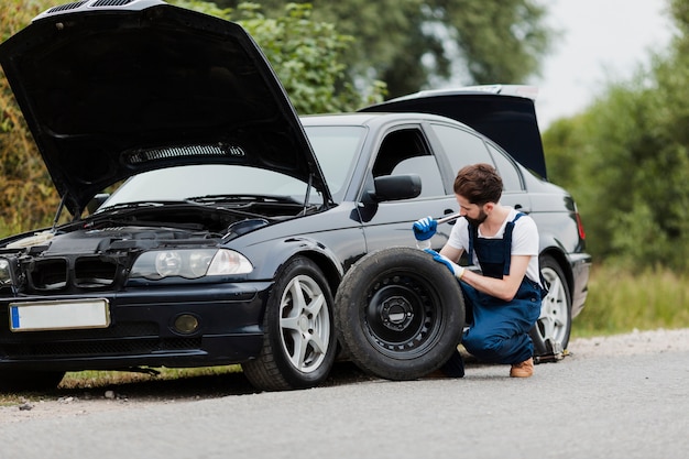 Long shot of man swapping tire