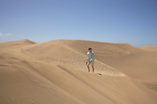 Free Photo long shot man with camera in the desert