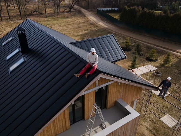 Long shot man with helmet sitting on roof