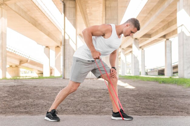 Long shot man working out with a red stretching band