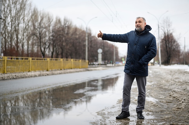 Long shot mature man waiting for a car