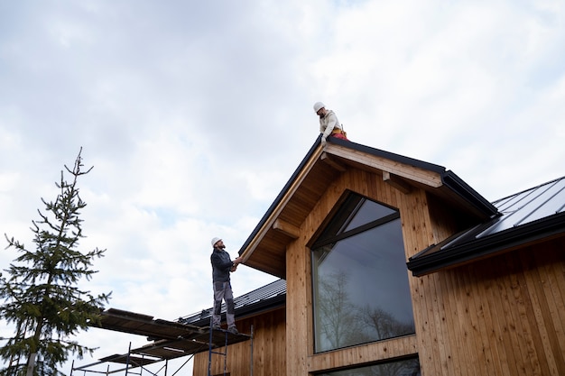 Free photo long shot men working on roof together