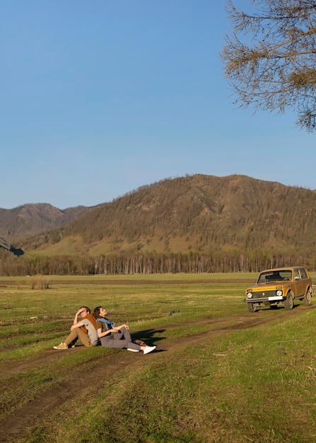 Free photo long shot people sitting on grass together