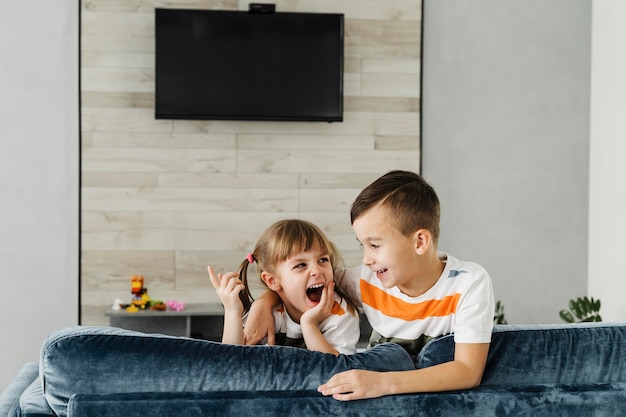 Long shot of siblings and television on the wall