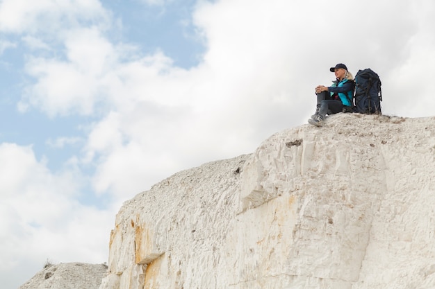 Free photo long shot traveler sitting on a mountain