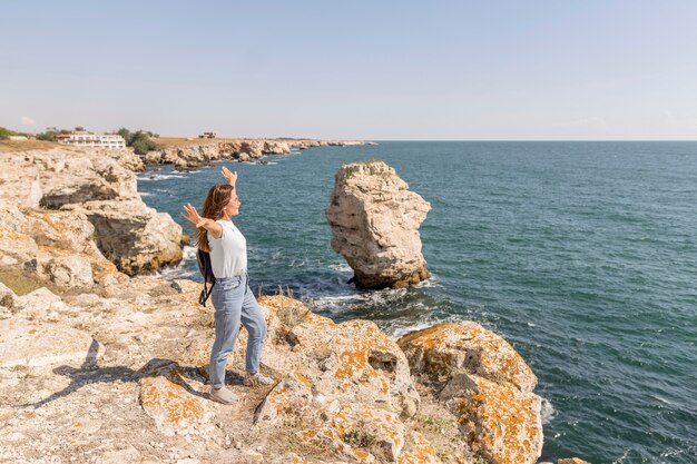 Long shot woman being enthusiast about the beach