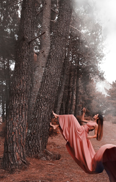 Long shot woman in dress climbing a tree