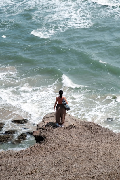 Long shot woman at seaside with yoga mat