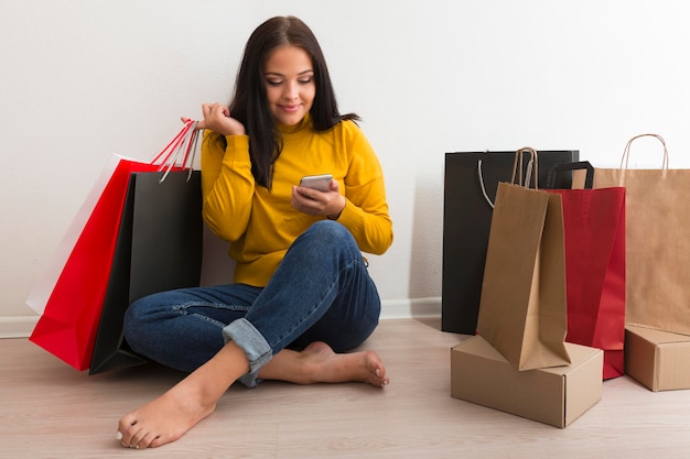 Long shot woman sitting next to shopping bags