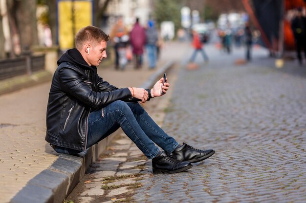 Long shot young man listening to music on earbuds outside