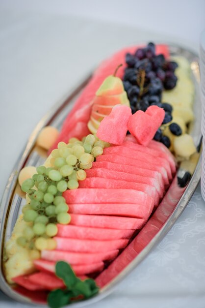 Long steel dish with grape, sliced apple and watermelon