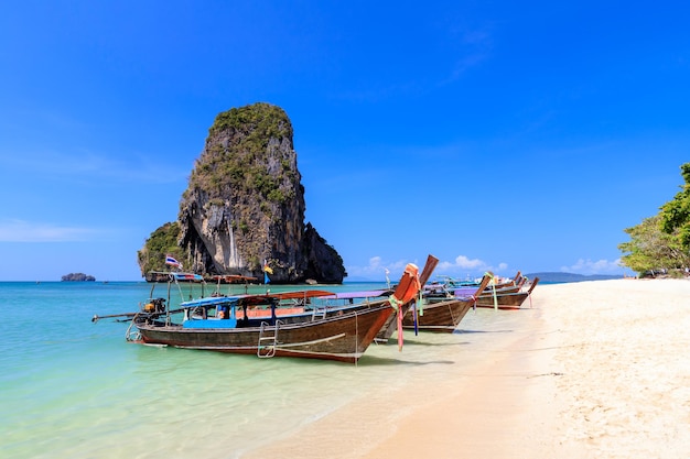 Long tail boat and turquoise crystal clear sea water with limestone cliff and mountain at Phra Nang Beach Krabi Thailand