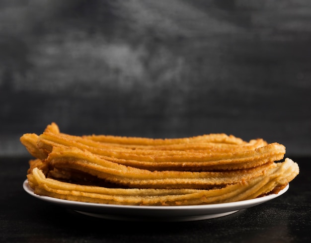 Free photo long view of white plate filled with churros