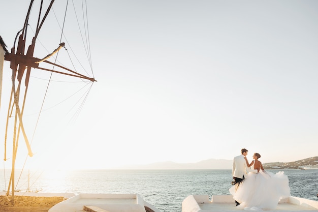 Look from afar at lovely wedding couple watching the sunset over the sea