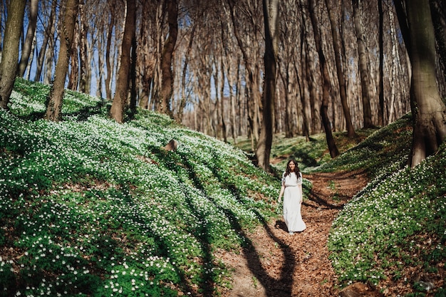 Free photo look from afar at woman in white walking in the green forest