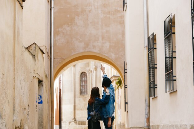 Look from behind at the couple of tourists watching something while walking around the city