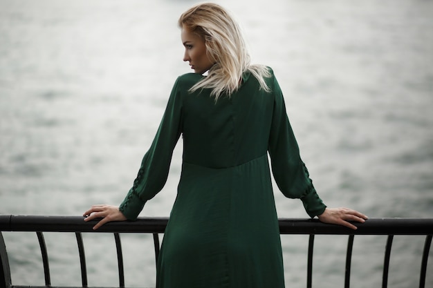 Free photo look from behind at dreamy woman in green dress standing before the river in new york