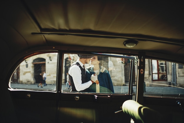 Look through the retro-car at a man and woman dressed in old-fashion style