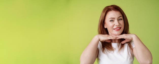 Free Photo looking good happy cheerful redhead middleaged 50s woman smiling delighted hold hands under chin accept flaws blemished like own skin condition apply aging creme cosmetics green background