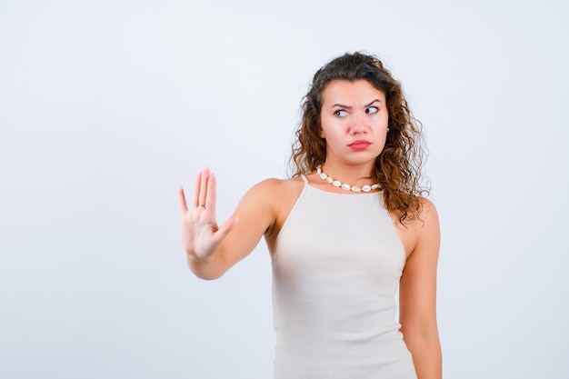 Looking left girl is showing stop gesture on white background