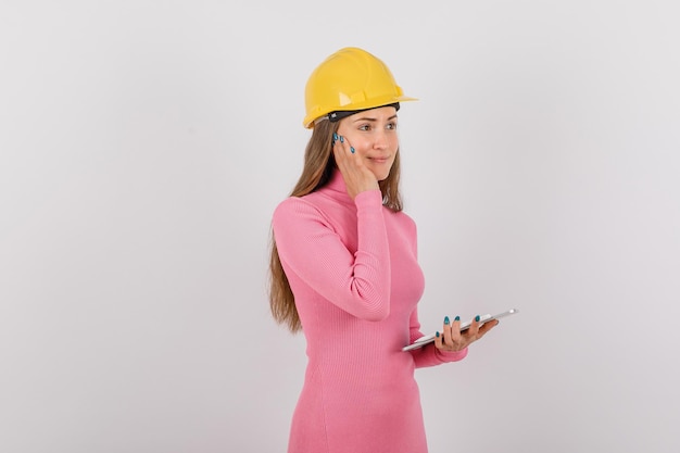 Looking right engineer girl is holding hand on cheek on white background