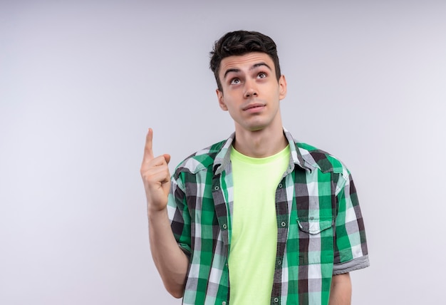 Looking to up caucasian young guy wearing green shirt points to up on isolated white background