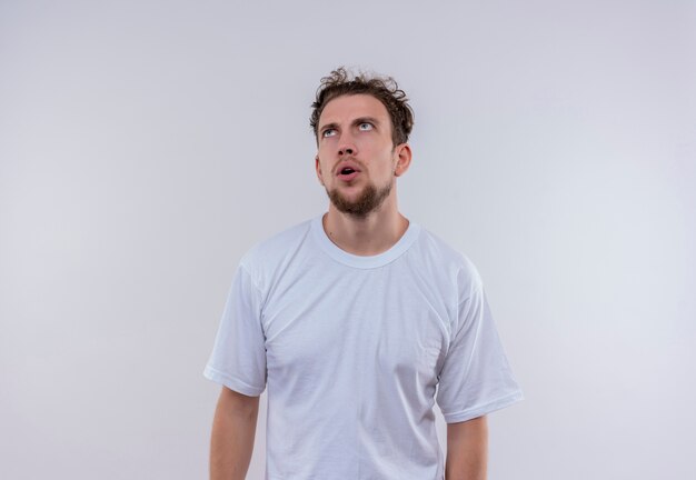 Looking at up thinking young guy wearing white t-shirt on isolated white background