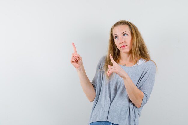 The looking up woman is pointing up with forefingers on white background