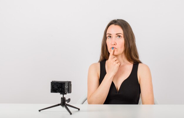 Looking up young girl is thinking by holding forefinger on lips on white background