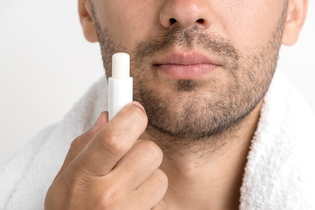 Lose-up of man with towel around his neck holding lip balm