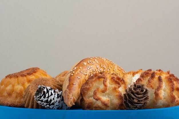 A lot of fresh delicious cookies with small pinecones on blue plate.