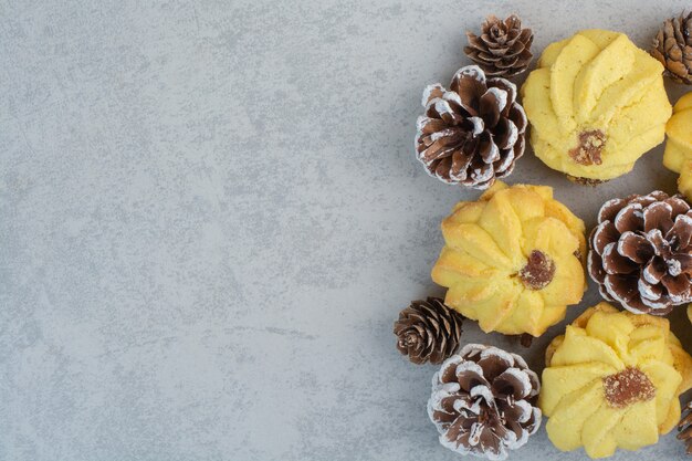 A lot of fresh delicious cookies with small pinecones on white table.