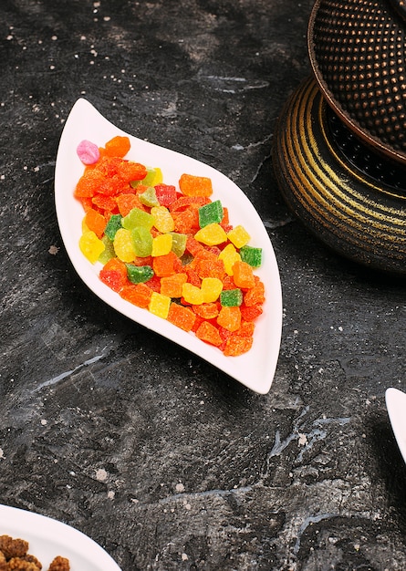 A lot of sweet colored jelly juicy marmelade in a plate on black table