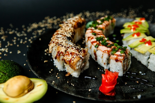 Lots of various types of sushi rolls topped with sesame seeds close-up view