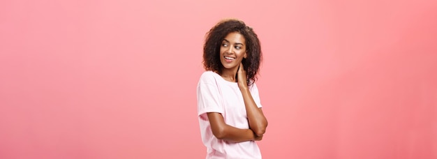 Free photo love in air come and say hi flirty sensual goodlooking african american young female student with afro hairstyle touching neck gently turning right gazing with curiousity and desire over pink wall