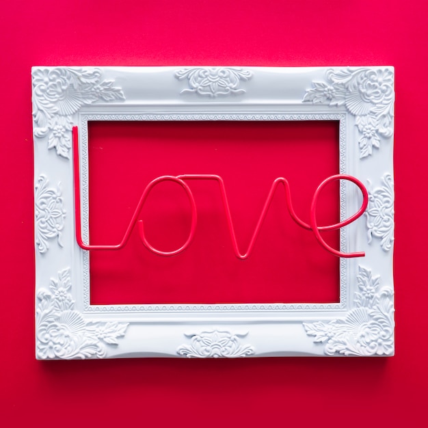 Free Photo love inscription with frame on red table