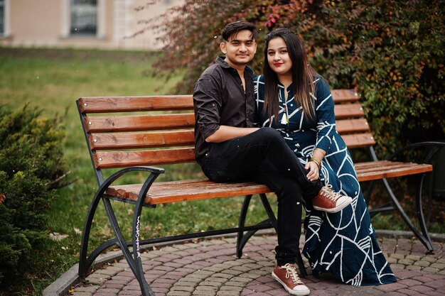 Love story of indian couple posed outdoor sitting on bench together