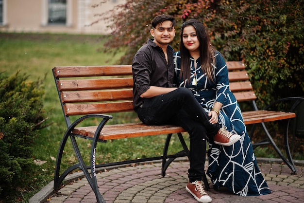 Love story of indian couple posed outdoor sitting on bench together