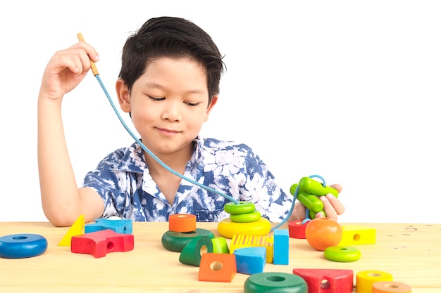 Lovely asian boy is play colorful wood block toy