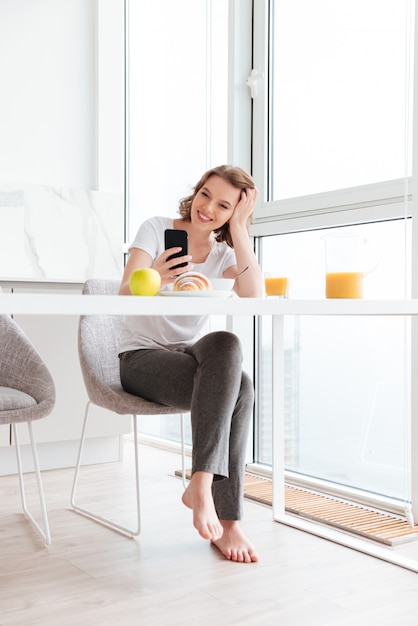 Free Photo lovely beautiful woman holding her head while reading message on smartphone at the kitchen