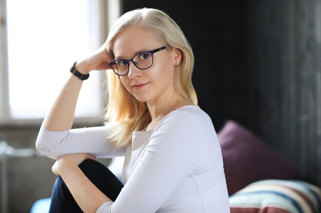 Lovely blonde woman with eyeglasses posing in white shirt