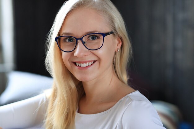 Lovely blonde woman with eyeglasses posing in white shirt