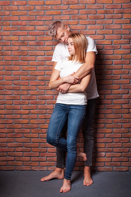 Lovely boyfriend and girlfriend spending time posing on brick wall