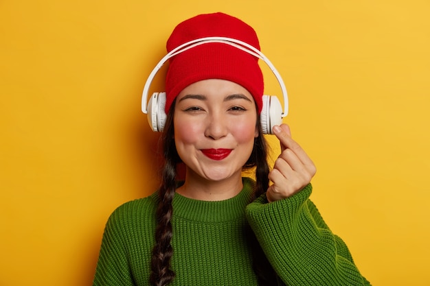 Free Photo lovely brunette woman in red hat and green jumper, listens audio track