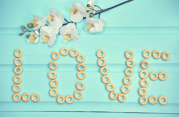 Free photo lovely bubliks put together in the word love on old blue wooden table with fresh spring flowers top view